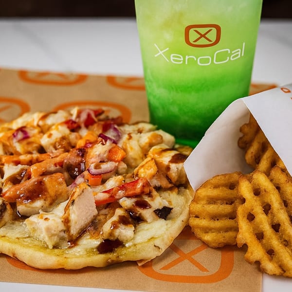 Xerocal meal with chicken flatbread, waffle fries, and a green drink with the Xerocal logo.