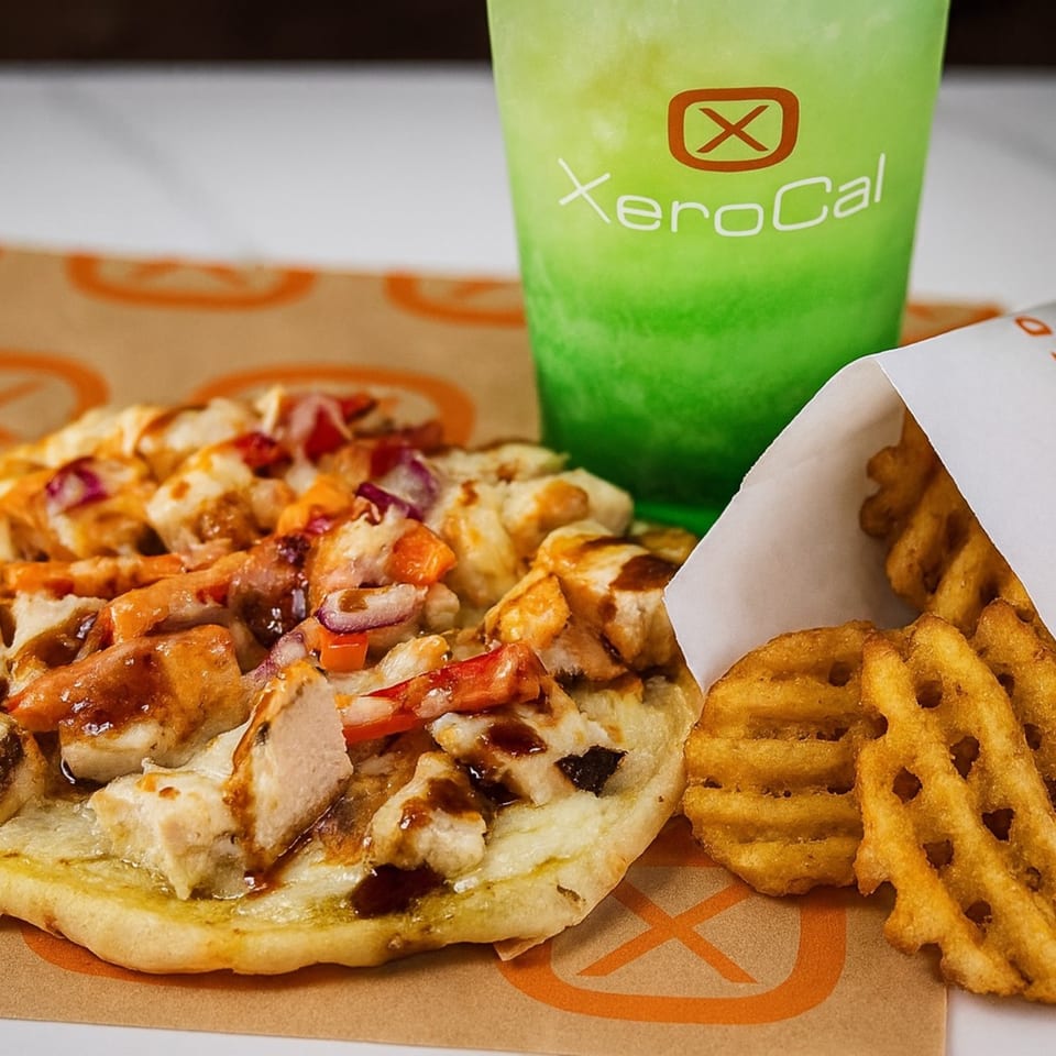 Xerocal meal with chicken flatbread, waffle fries, and a green drink with the Xerocal logo.