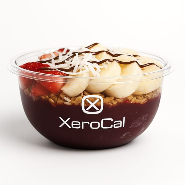 Xerocal açaí bowl with granola, strawberries, bananas, shredded coconut, and chocolate drizzle.