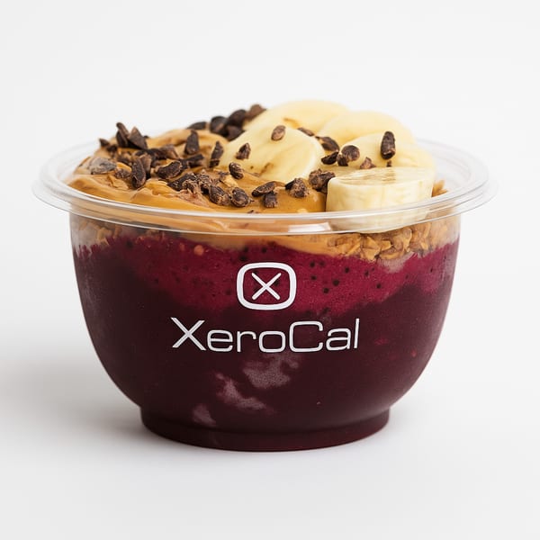 Xerocal acai bowl with peanut butter, banana slices, and chocolate chips in a clear cup.