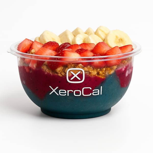 Xerocal acai bowl with red and blue layers, topped with granola, strawberries, and bananas.